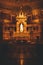 Vertical image of a dark church alter with an illuminated statue shrine