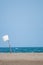 Vertical image of deserted beach with a white flag made of a wooden stick stuck in the sand and a plastic bag blown by the wind