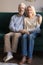 Vertical image elderly couple hugging sitting on couch