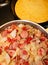 Vertical image of fried cabbage, sausage, onions, tomatoes and pan of cornbread