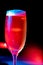 Vertical image of a full glass of Champaign in the dark background with red and blue lights