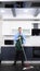 Vertical image. handsome man in tie and apron mops the floor in the kitchen