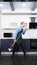 Vertical image. handsome man in tie and apron mops the floor in the kitchen