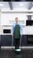 A vertical image. handsome man in tie and apron sweeping the kitchen floor