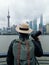 Vertical image of a man traveler with holding camera is looking at View of Shanghai city skyline