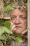 Vertical image of a mature man spying through an ivy plant