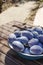 Vertical image.Metal bowl of ripe pulms on the wooden table, outdoor.Natural light