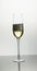 Vertical image of open bottle pouring champagne into single tulip glass on white background