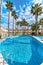 Vertical image palm tree around empty swimming pool with blue water inside residential urbanization