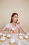 Vertical image of pensive woman by the table with cakes