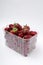 Vertical image.Plastic container full of fresh just picked strawberries on the white background
