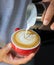 Vertical image of pouring milk to espresso coffee make latte art