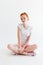 Vertical image of pretty ginger girl sitting on the floor