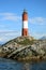 Vertical image of red and white striped Les Eclaireurs lighthouse on a rocky islands, symbol of Beagle channel, Ushuaia, Tierra de