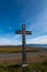 Vertical image, simple oak wood catholic cross near curving asphalt road