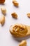 Vertical image of spoon with peanut butter and nuts on white surface