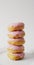 Vertical image of stack of donuts with pink frosting on grey background