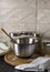 Vertical image. Steel bowl, glass jars, wooden board on the black litchen table against wall