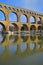 Vertical image of three arch level of Pont du Gard with clear reflection on Gardon River