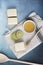 Vertical image of three lemon cakes with lime slices and a pot of honey