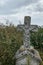 Vertical image. Unnamed gravestone on old abandoned city cemetery. Weathered stone cross on abandoned graveyard