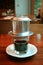 Vertical Image of Vietnamese Drip Coffee Slowly trickling Into Transparent Cup