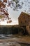 Vertical image of a waterfall at the historic Yates Mill County Park in Wake County, North Carolina at sunset in autumn