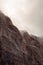 A vertical image of winter storm clouds drifting over the snow laced towering red sandstone cliffs of Zion national park