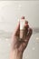 Vertical image.Woman holding bottle of beige colored nail polish against bokeh lights