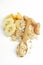 Vertical image.Wooden spoon, heap of oatmeal, corn flakes, pieces of banana, peach, plum on the white surface.Delicious ingredient