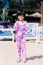 Vertical imaged. Happy Asian cute girl standing and posting take a picture. Child looking at camera. Sweet smiling. At the beach.