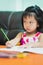 Vertical images. Portrait of cute Asian girl showing dissatisfaction while doing homework.