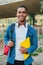 Vertical individual portrait of a african american student young man carrying a backpack and note books at university