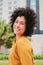 Vertical individual portrait of hispanic young adult woman with curly hair and white teeth smiling looking at camera