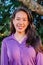 Vertical individual portrait of one adult woman smiling and looking at camera at backyard. One happy asian female