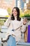 Vertical individual portrait of one brunette lady doing a call with a cell phone sitting on a bench in a city street