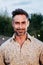 Vertical individual portrait of one middle aged handsome man standing outside, smiling and looking at camera with