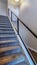 Vertical Indoor stairs of home with metal handrail and gray carpet on the treads