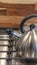 Vertical Kettle on the cooktop against wooden chopping board and tile backsplash