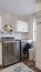 Vertical Laundry room interior with cabinets wahing machine and dryer against white wall