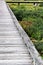 A vertical leading view of a grey old boardwalk