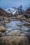 Vertical long exposure of the Haba glacier streaming through rocks with a background of mountains