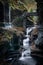 Vertical long-exposure scenic view of the waterfalls falling down a cascade under a historic bridge