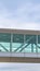 Vertical Looking up at an empty skybridge with a cloudy blue sky in the background