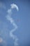 Vertical low angle shot of a red plane maneuvring in the sky and leaving a huge white trail