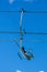 Vertical low angle shot of a ski lift hanging on a wire in a blue sky