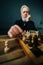 Vertical low-angle view of focused bearded mature male performing move with pawn piece on wooden chessboard, selective