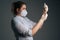 Vertical medium studio shot of nurse in blue gloves and face mask holding and filling up vaccine to syringe on black