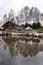 Vertical mesmerizing view of the rocky Geisler Alm mountains with a rural wooden house