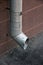 Vertical metal tinplate drain pipe with bell at wall on street closeup